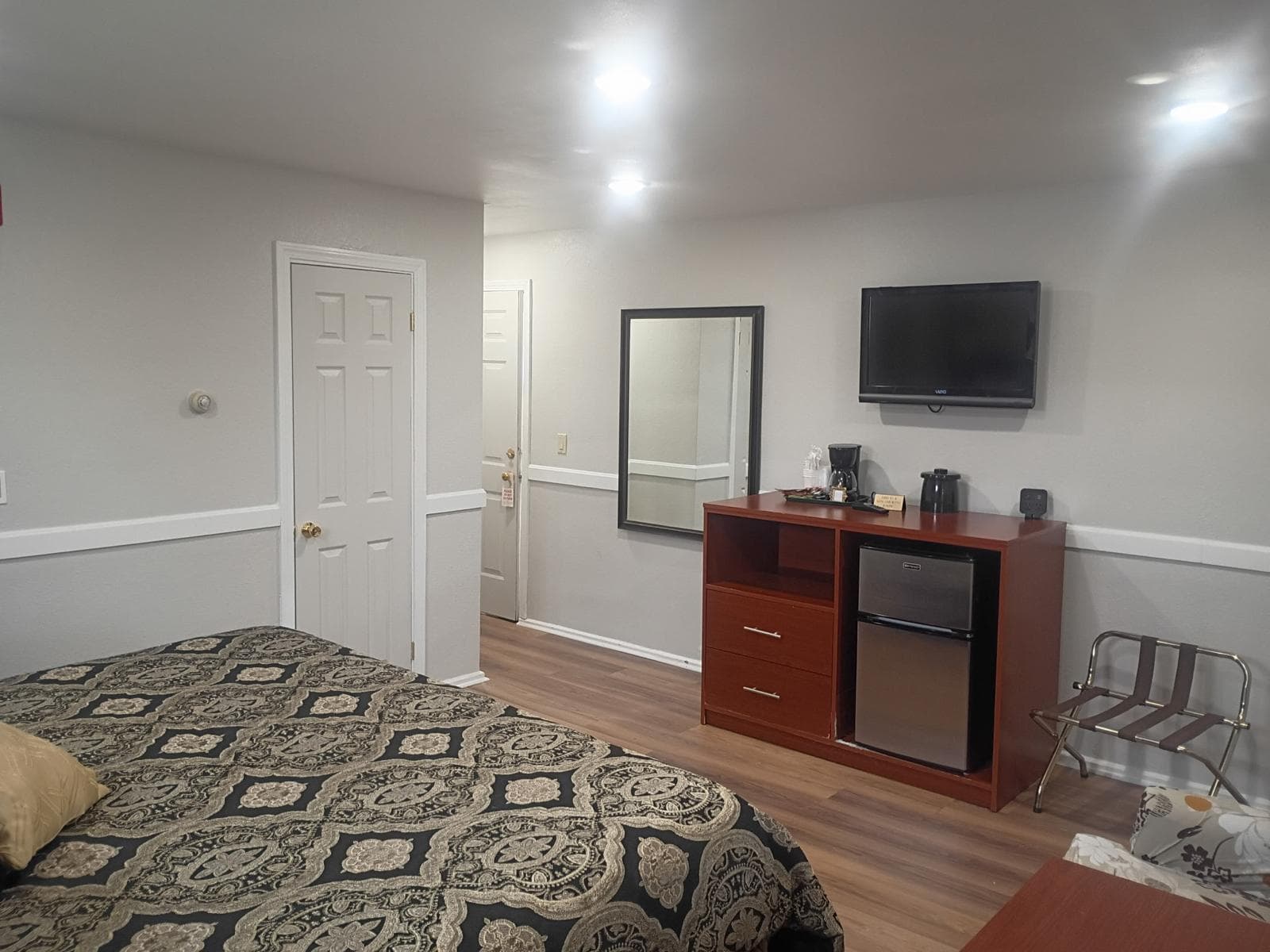 Room entry area with wall-mounted TV, dresser and mini-fridge at Briarcliff Motel