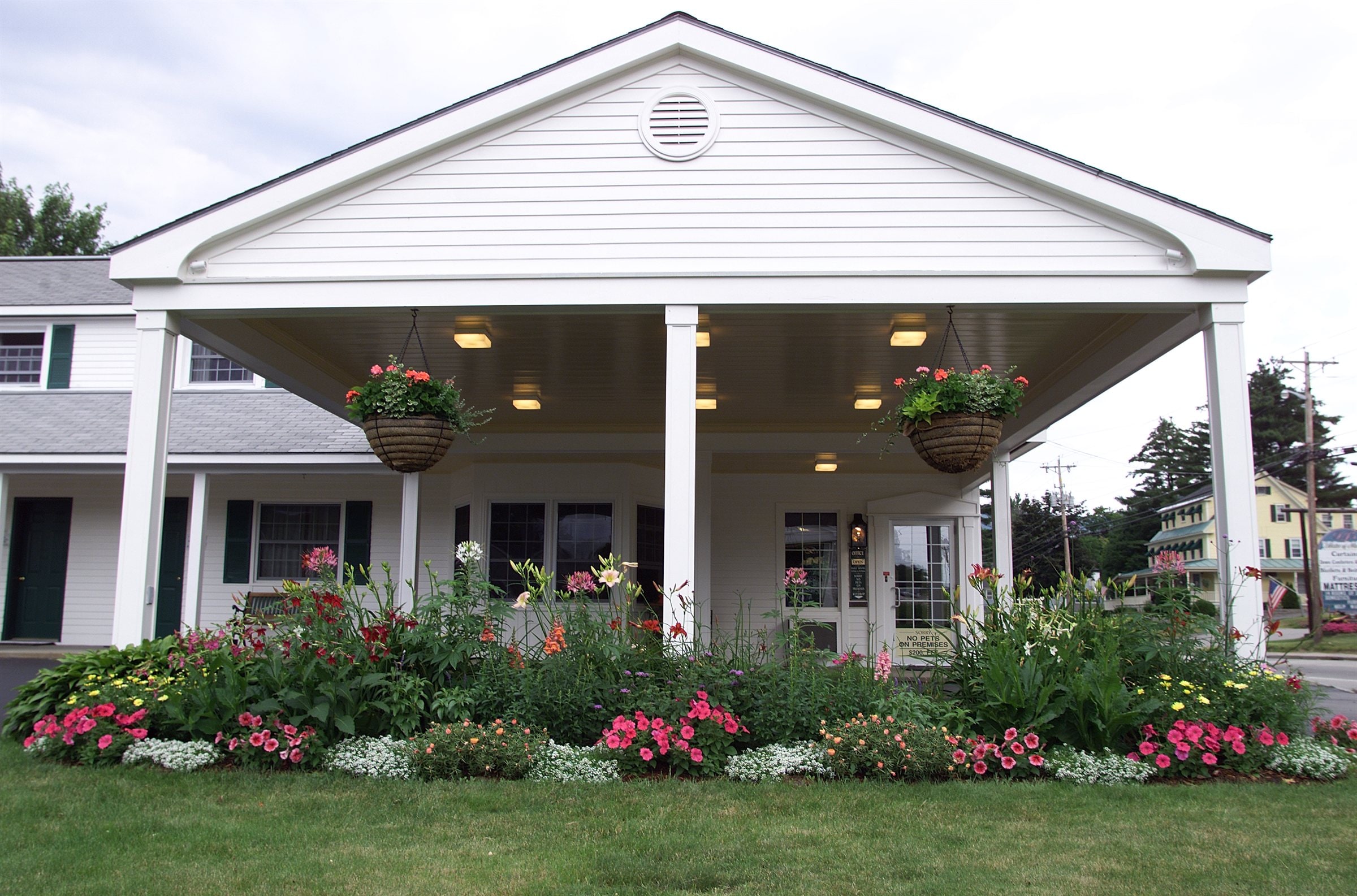 Briarcliff Motel front porch with hanging flower baskets and a vibrant summer flower bed