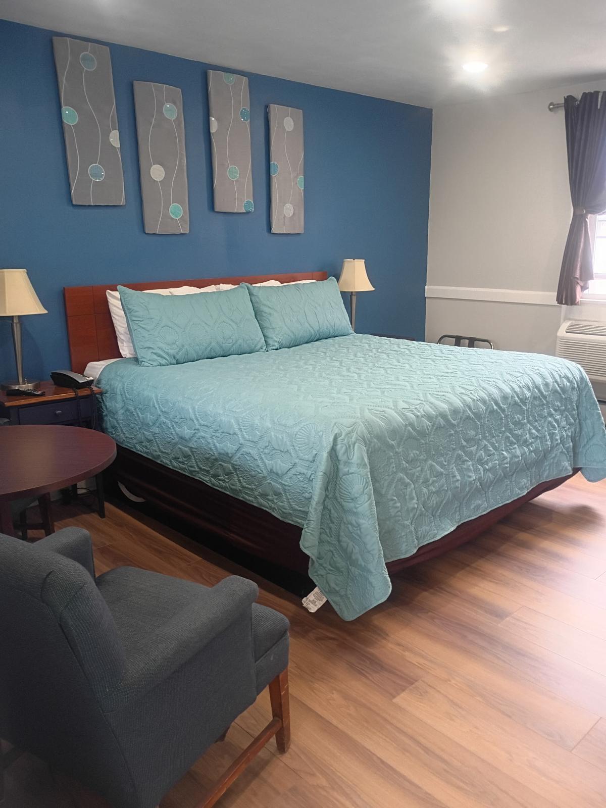 King bed with teal quilted bedspread and coastal-style wall art